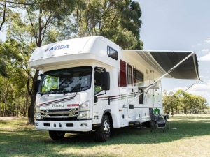 Avida motorhome parked in a scenic outdoor setting, featuring an extended awning and outdoor seating, highlighting safety and comfort for travel.