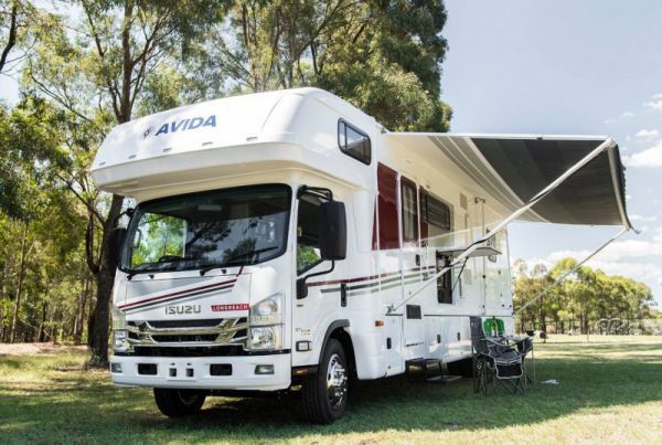 Avida motorhome parked in a scenic outdoor setting, showcasing a spacious design with an extended awning and outdoor seating, emphasizing the comfort and lifestyle of motorhome living.