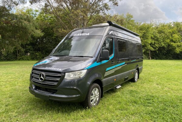 Avida Dimension campervan parked on green grass, showcasing sleek design and modern features, ideal for road trips and outdoor adventures.