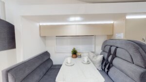 Modern motorhome interior featuring a cozy seating area with a table, plush gray upholstery, and natural decor, highlighting comfort and convenience for Gold Coast travelers.