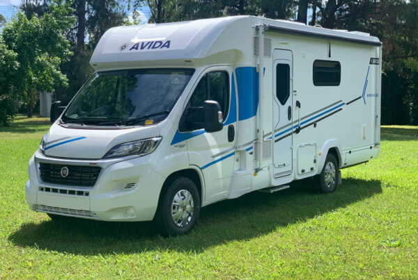 Avida motorhome parked on green grass, showcasing a modern exterior design with blue accents and a Fiat chassis, ideal for Australian road trips.