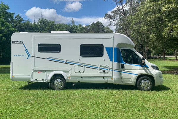 Avida Birdsville motorhome parked on green grass, showcasing its sleek exterior design and spacious side slide-out, ideal for Gold Coast vacations.