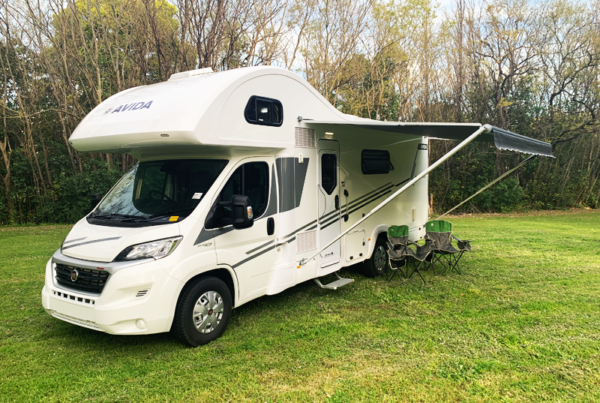 Avida motorhome parked on grass with awning extended, showcasing outdoor seating area, ideal for camping and travel in Queensland.