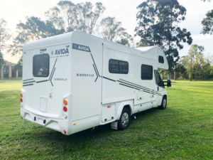 Avida Birdsville campervan parked on green grass, showcasing its rear and driver's side features, emphasizing outdoor storage suitability for campervans in Queensland.