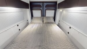 Electric drop-down bed in a modern Avida motorhome, featuring a cozy mattress and ambient lighting, enhancing comfort for travelers.