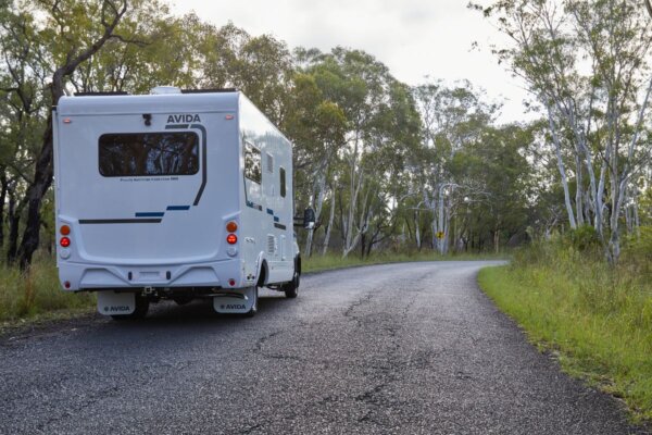 Avida Bruny motorhome on a winding road surrounded by greenery, showcasing its sleek design and practical features for touring.