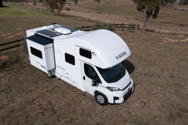 Avida Silverton motorhome parked in a grassy landscape, featuring a sleek design, slide-out section, solar panel, and spacious exterior for outdoor living.