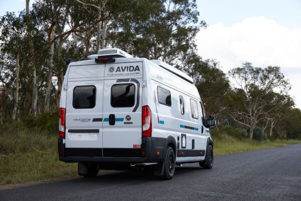 Avida Trek campervan parked on a scenic road, showcasing its sleek design, solar panel, and compact build, emphasizing travel versatility and modern features.