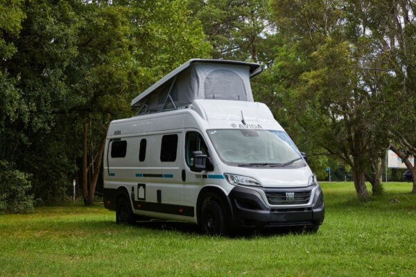 Avida Trek campervan parked in a grassy area, featuring a pop-top roof and sleek exterior design, highlighting its compact size and suitability for outdoor adventures.