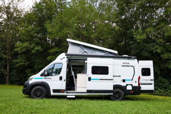 Avida Trek campervan parked on grass with pop-top raised, showcasing its compact design and functional layout for adventurous travel.