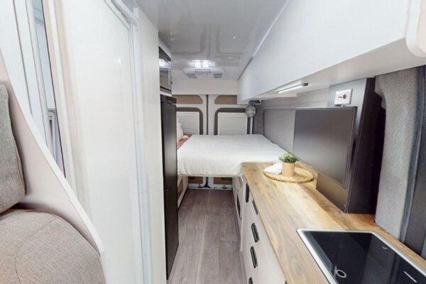 Interior view of Avida Trek campervan showcasing compact kitchen, dinette area, and fixed bed, emphasizing smart design and space optimization for travel.