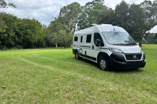 Avida Trek campervan parked on green grass in a natural setting, showcasing its compact design and features, ideal for outdoor adventures.